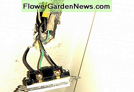 Bryteren er trukket fra veggen nÄr strÞmmen er slÄtt av, og utsetter ledninger og skruer som holder dem. Den grÞnne jordledningen gÄr til en grÞnn jordskrue. The switch has been pulled from the wall with the power turned off, exposing the wires and screws holding them. The green ground wire goes to a green ground screw.