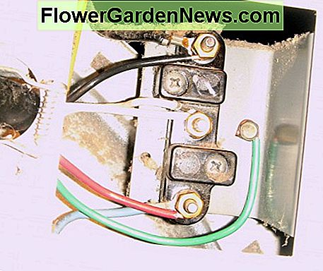 Die vieradrige Schnur wurde von der Trocknerwand gelöst und kann von den Anschlüssen getrennt werden. Achten Sie besonders auf die weißen und grünen Drähte. The four-pronged cord has been loosened from the dryer wall and is ready to be disconnected from the terminals. Pay particular attention to where the white and green wires go.
