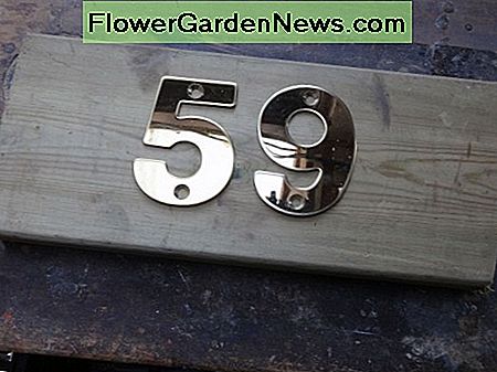 Nieuwe messing huisnummers test gelegd op het dekwerk offcut New brass house numbers test laid on decking offcut