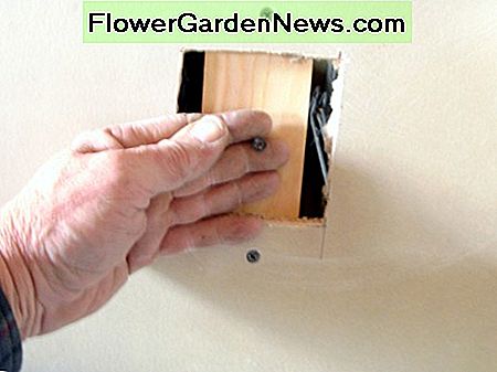 Met behulp van een schroef als een handvat om de steun op zijn plaats te houden tijdens het schroeven door de bestaande gipsplaat. Using a screw as a handle to hold the backing in place while screwing through the existing drywall.