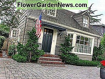 มีบันไดอิฐและหน้าต่างเบย์สองหน้าต่าง Dormer และธงอเมริกัน With brick steps and bay window, two dormer windows, and an American flag.