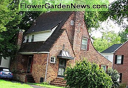 Tudor-Revival-Haus mit Ziegelsteinverkleidung und steilem SchrÀgdach. Tudor revival home with brick siding and steep pitched roof.