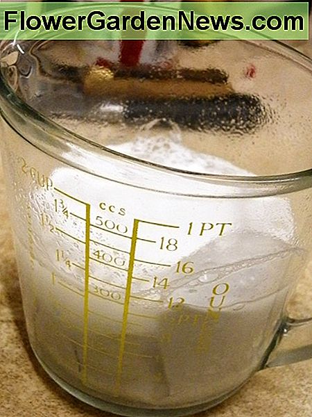 a frothy solution of soda crystals, hot water and aluminium foil in a glass measuring jug