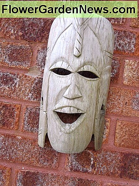 Mocking mask hanging on a red brick wall.